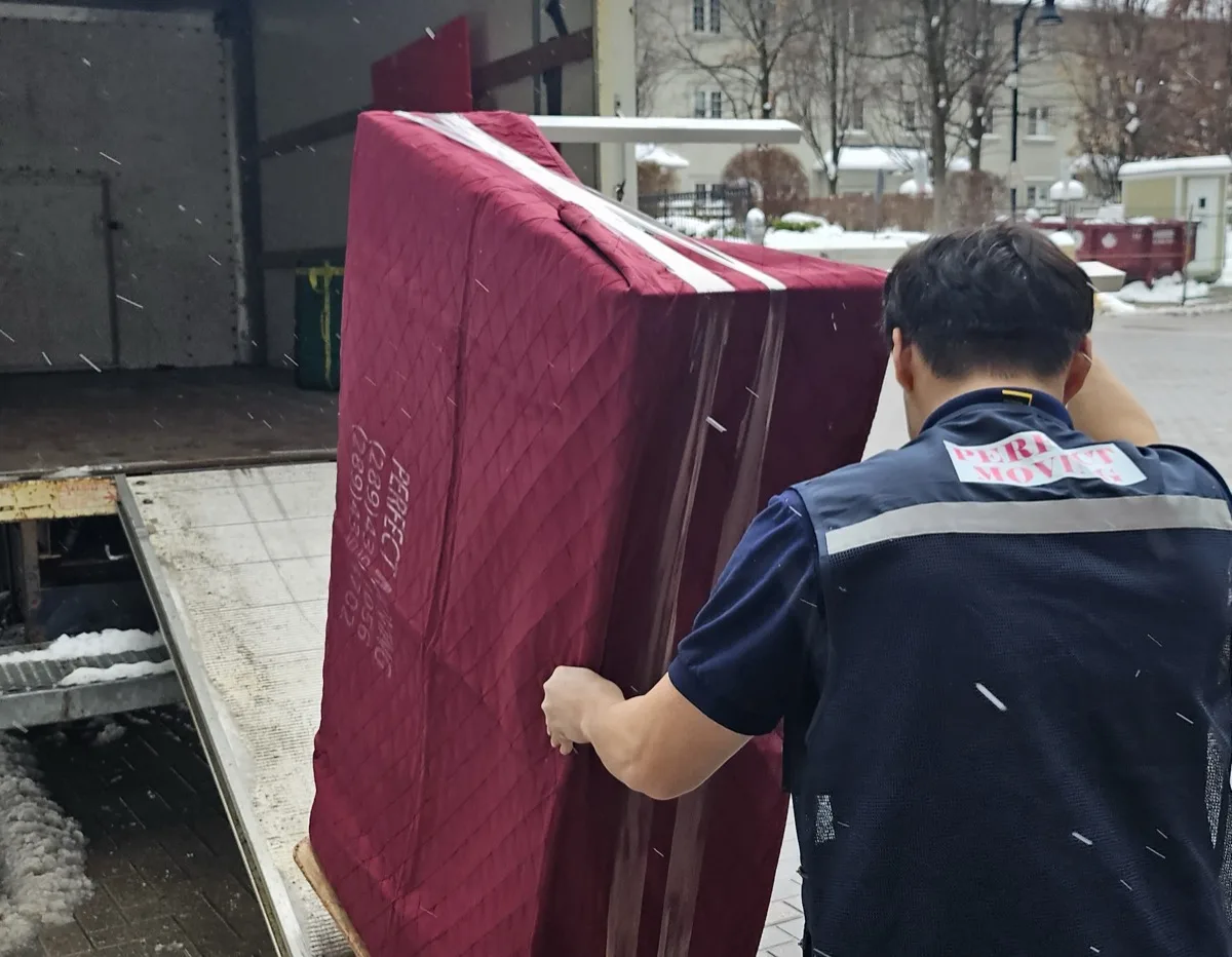 Perfect Moving mover loading a wrapped mattress into the truck